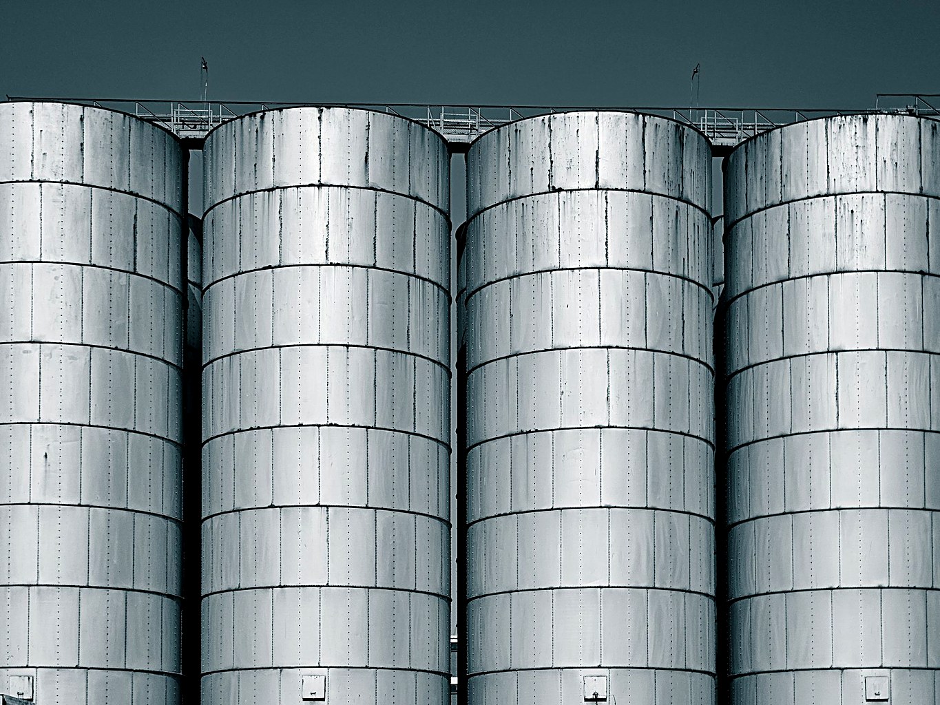 Rows of large welded steel storage silos at an industrial plant