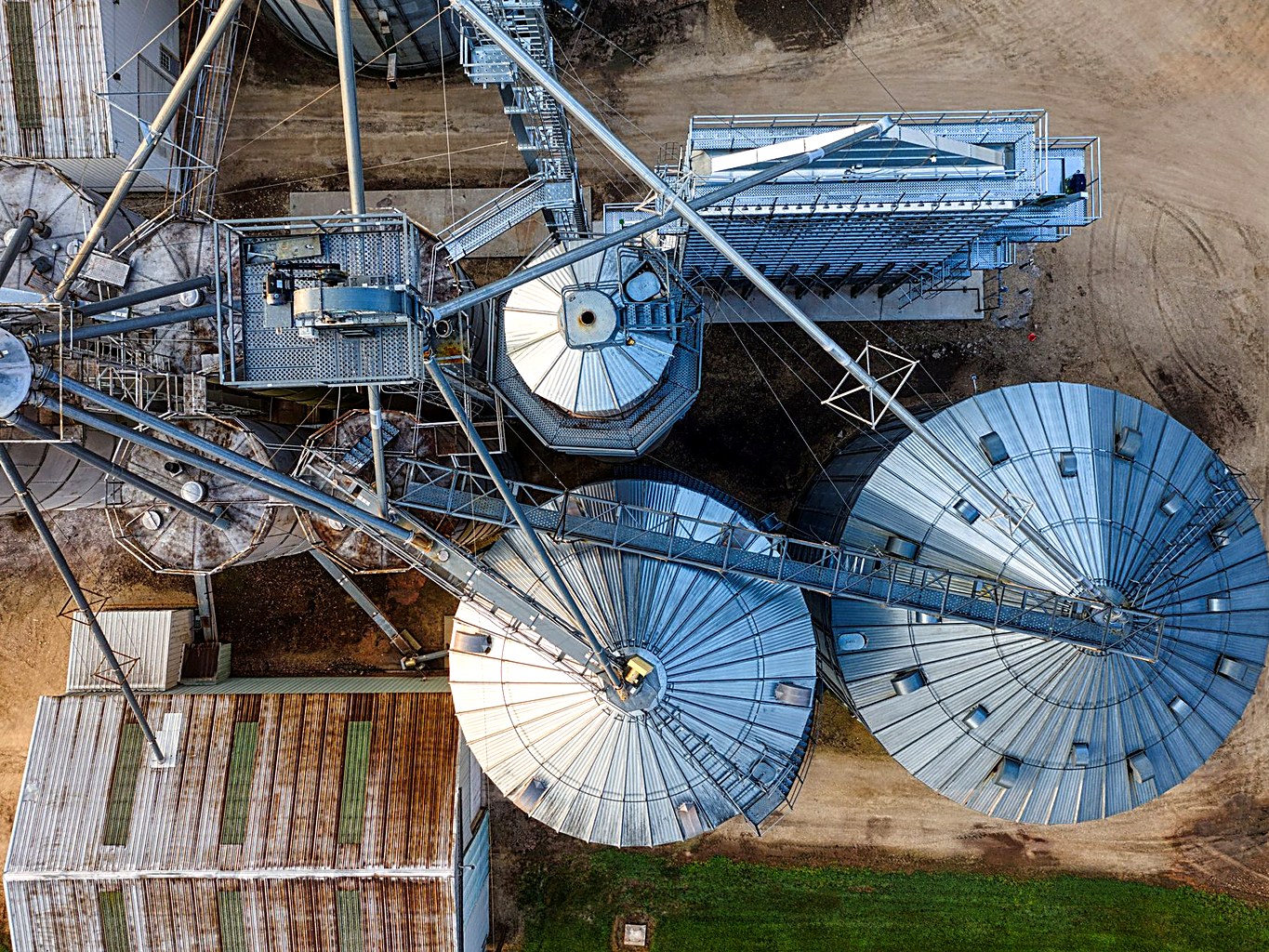 Aerial view of a corrugated steel grain silo cluster at a farm storage site