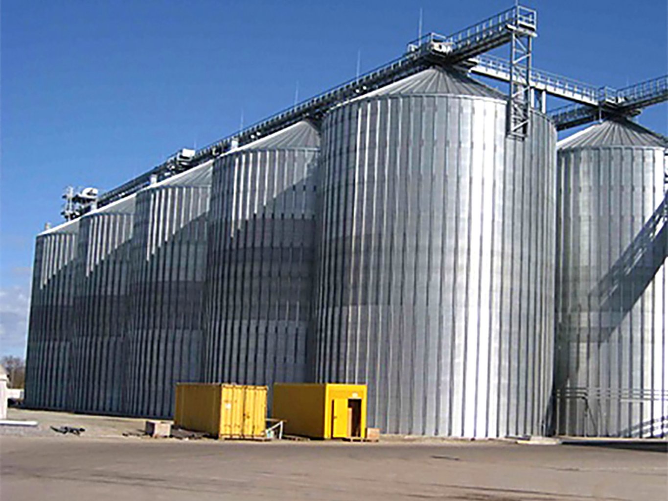 Corrugated bolted steel silos with catwalks storing raw grain at a feed mill